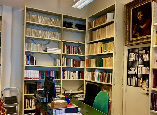 pokój roboczy ze ścianami zastawionymi regałami; pośrodku biurko ze stacją roboczą